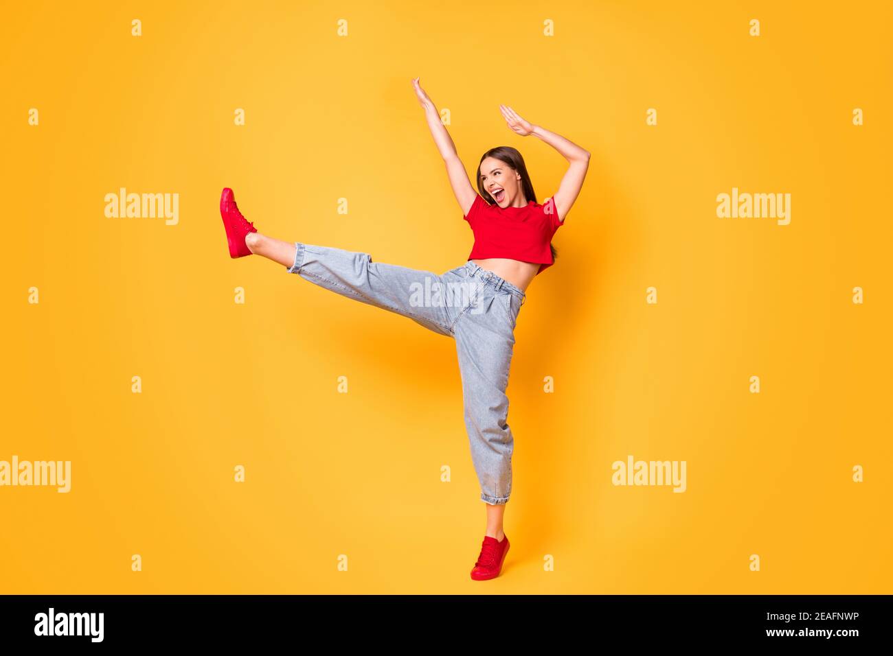 Full size photo youngster girl rejoicing raise leg hands dance floor party wear red crop top jeans isolated yellow color background Stock Photo
