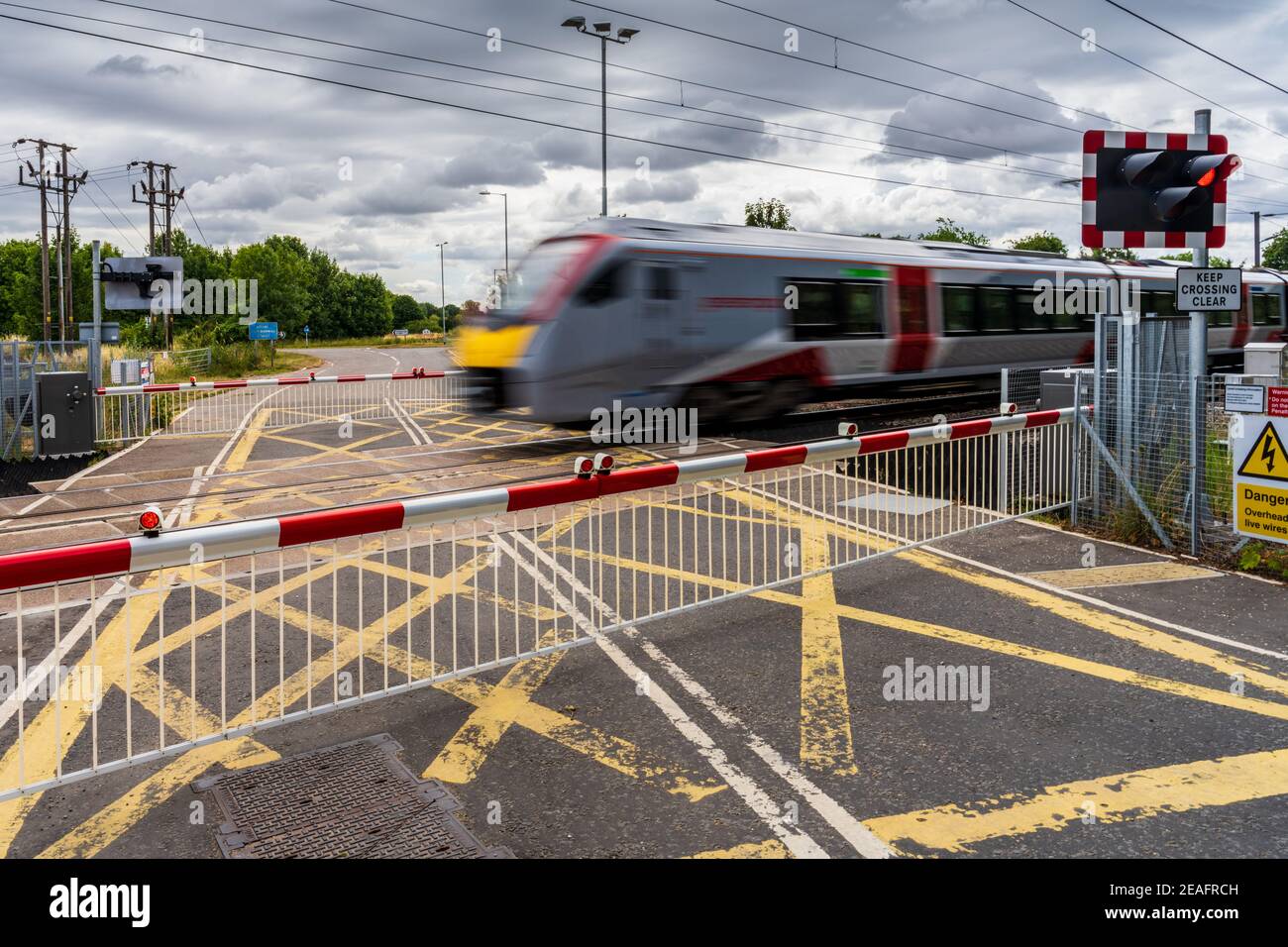 Level Crossing UK - Greater Anglia Stadler Bi-Mode FLIRT train passes through a level crossing in South Cambridgeshire. Stock Photo