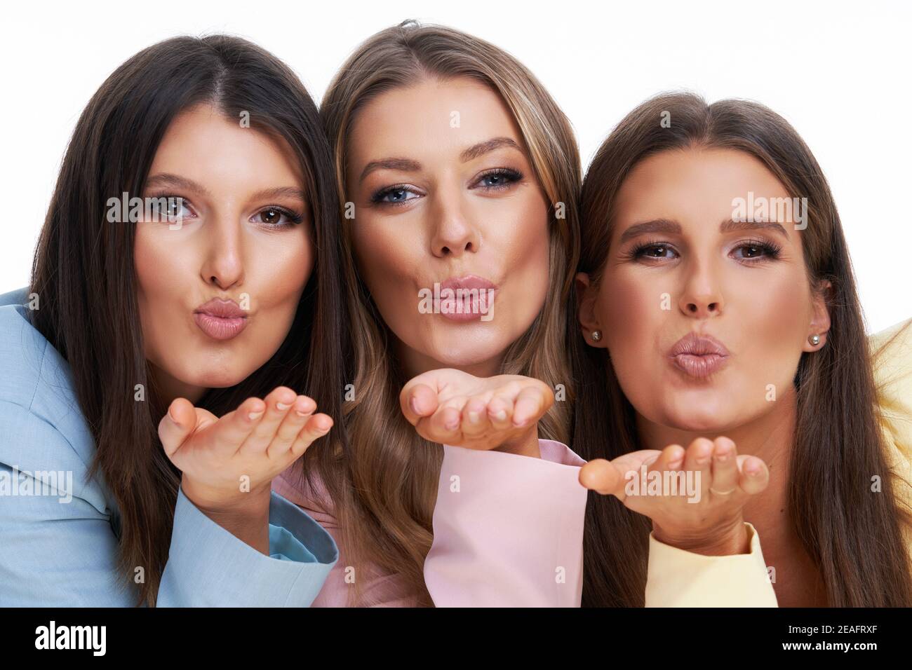 Three women in pastel suits posing over white background Stock Photo