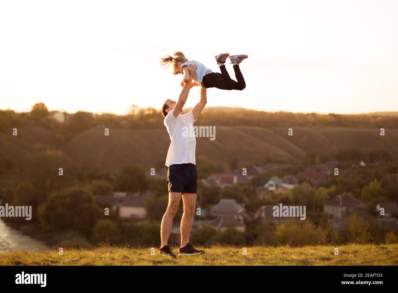 Father and daughter have fun together. Dad throws his daughter up in sky Stock Photo