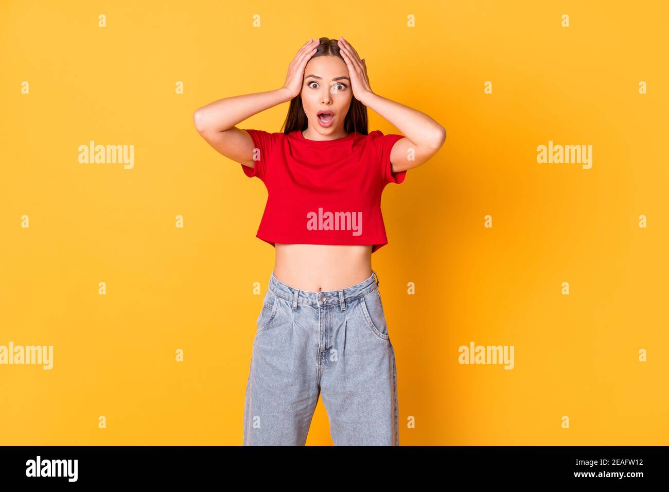 Photo of shocked terrified lady hands on head open mouth wear red crop top jeans isolated on bright yellow color background Stock Photo