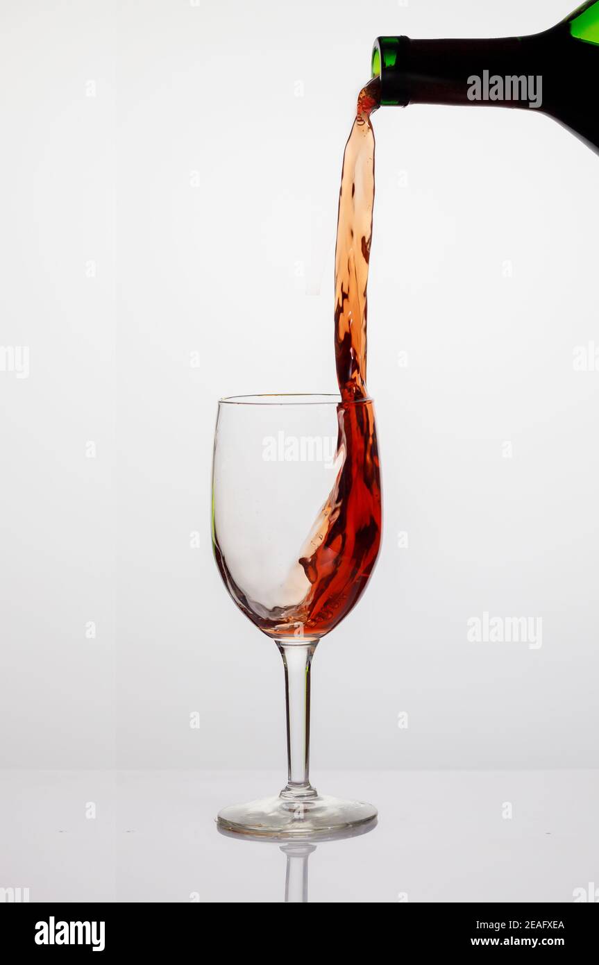 Pouring red wine into wine clear glass on white background Stock Photo Alamy