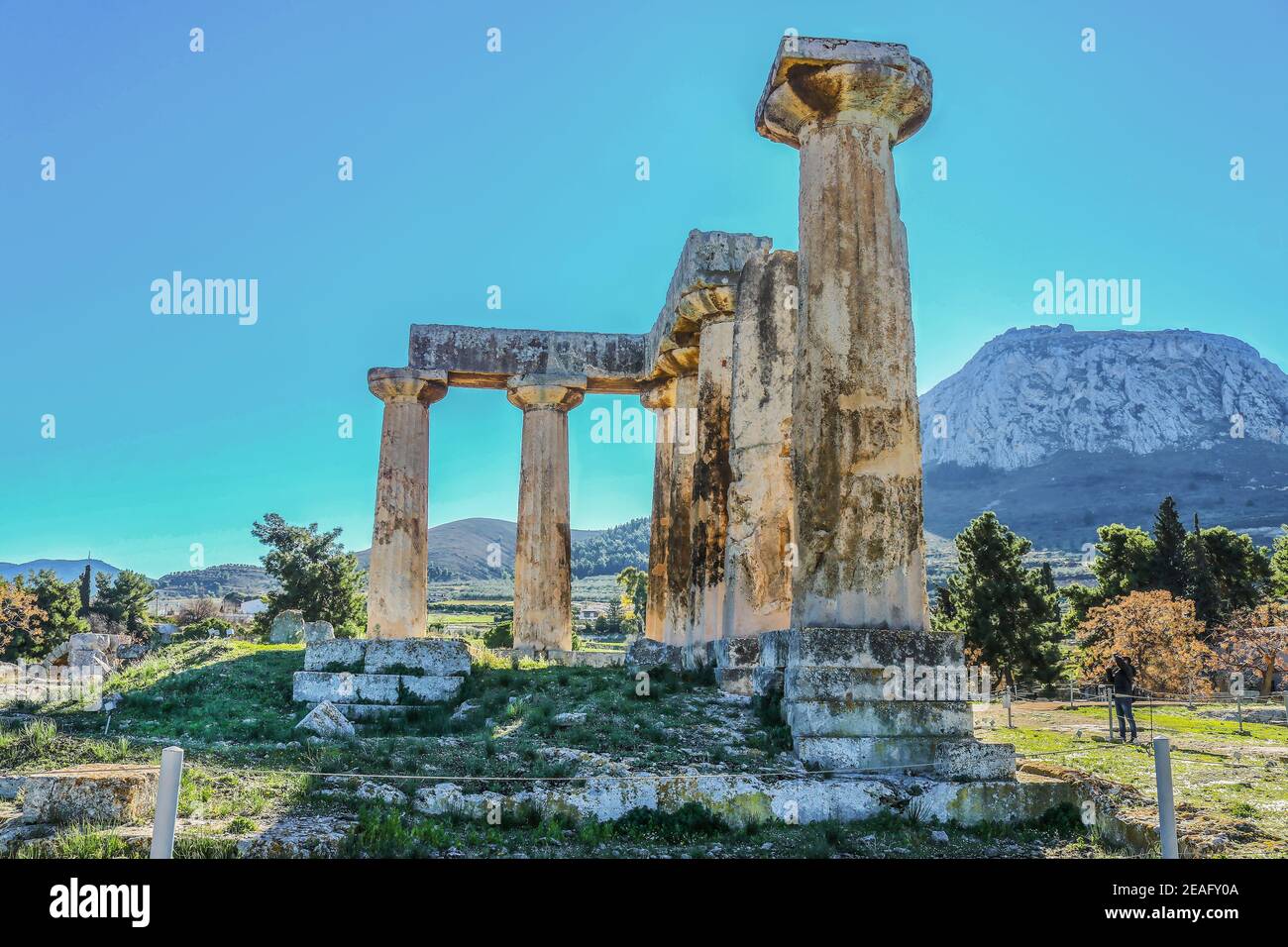 Columns in ruins of Temple of Apollo with Acrocorinth the acropolis of ancient Corinth - a monolithic rock overseeing the ancient city of Corinth Gree Stock Photo