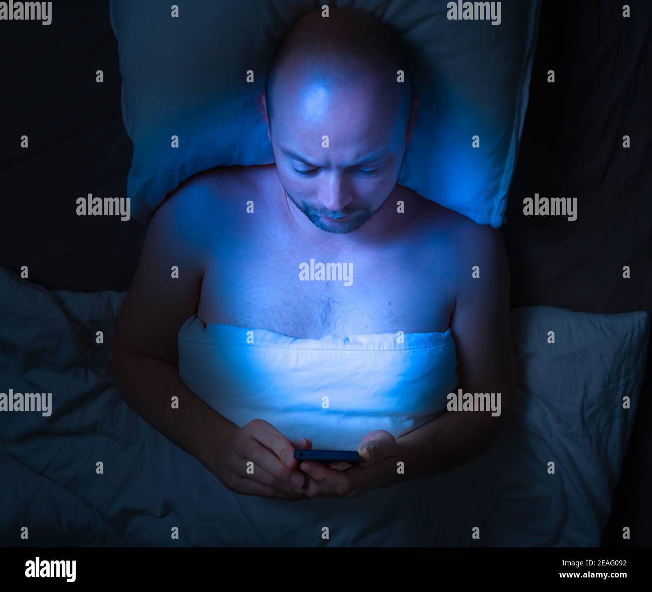 Man using his phone in bed at night . Stock Photo