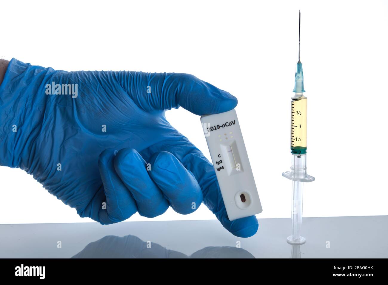 Vaccine dose in syringe and male doctor hand in blue glove holds corona virus test, white background, selective focus Stock Photo