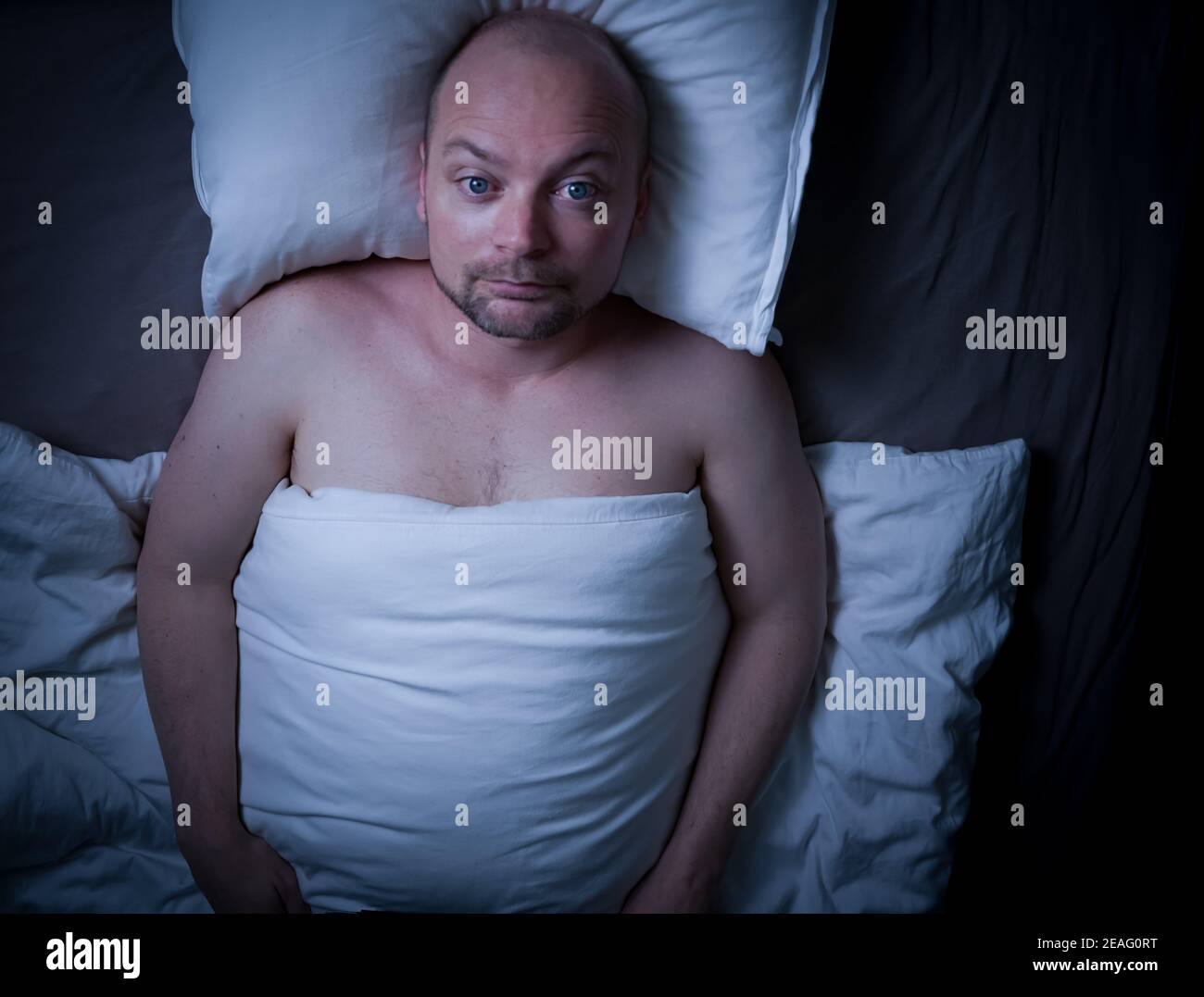 Man lying in bed, stressed, worried and cant sleep staring at the ceiling.  Stock Photo