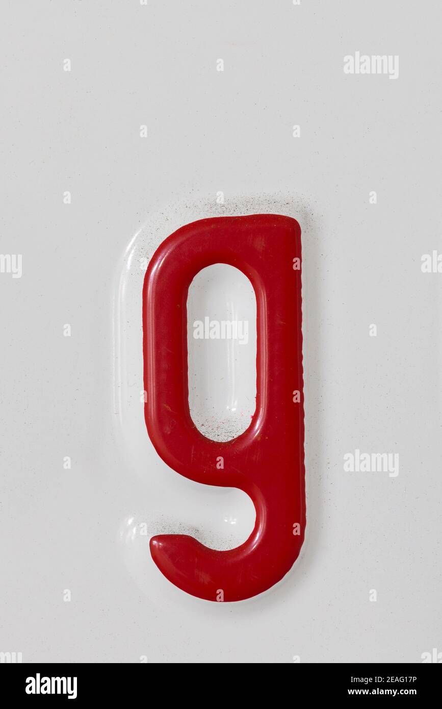 Embossed red letter g on a white tin plate Stock Photo