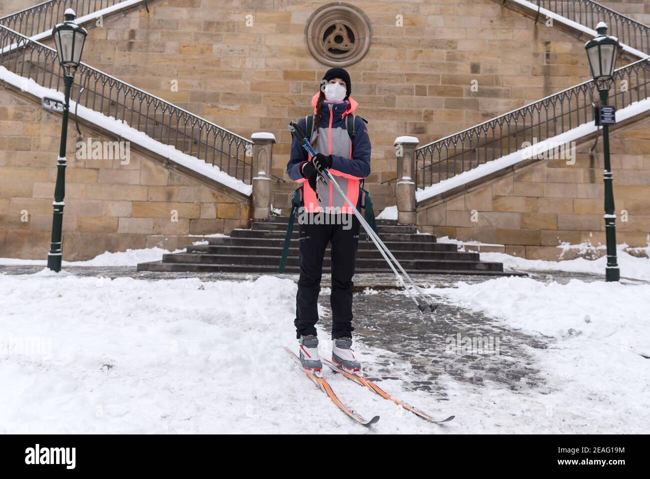 A woman, wearing a facemask as a preventive measure against the spread of coronavirus, cross-country skis under the iconic Charles Bridge.Heavy snowfall across the Czech Republic has disrupted rail, road and public transport. Stock Photo