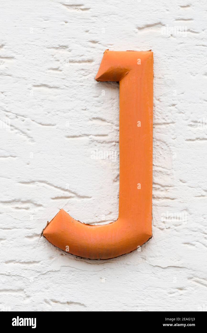 Orange letter J on a white house wall Stock Photo