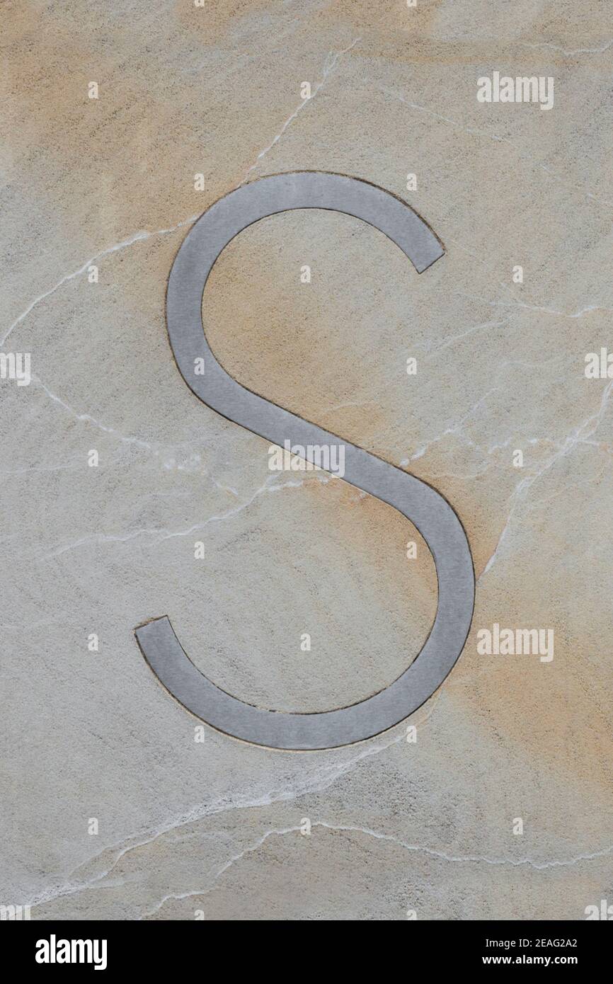 Metal letter S, embedded in sandstone Stock Photo