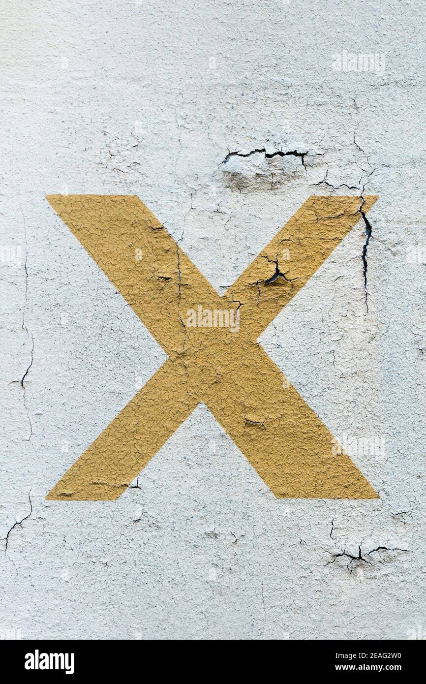 Mustard yellow letter x painted on a wall Stock Photo