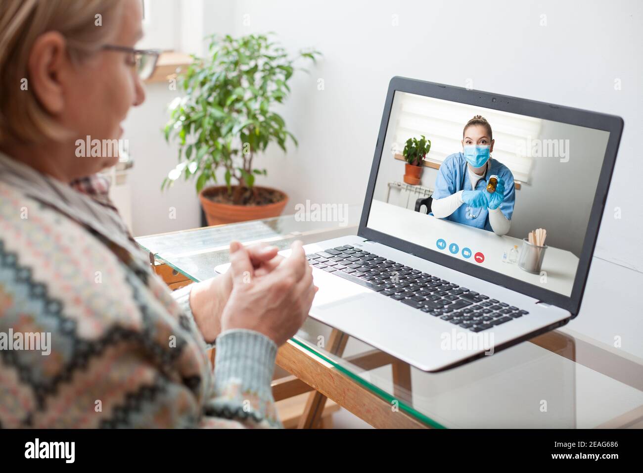 Young female doctor consulting with elderly woman over video help line virtual medical appointment,GP prescribing medication to senior patient Stock Photo
