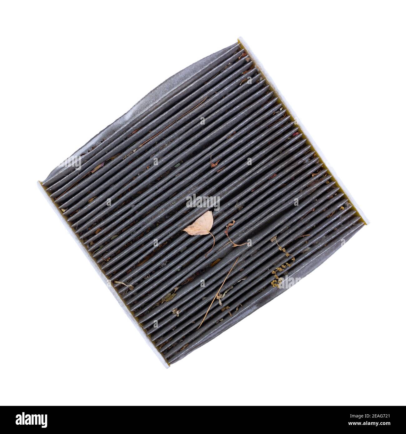 Dirty cabin air filter at an angle with dried leaves and dirt top view isolated on a white background. Stock Photo