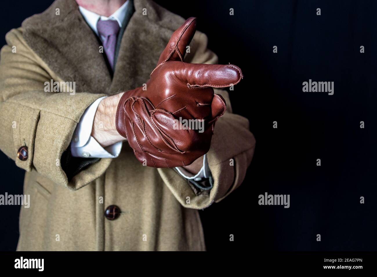 Portrait of Man in Coat and Suit Pointing Finger Gun Gesture on Black Background. Film Noir Secret Agent Spy. Playing Detective Action Hero Stock Photo