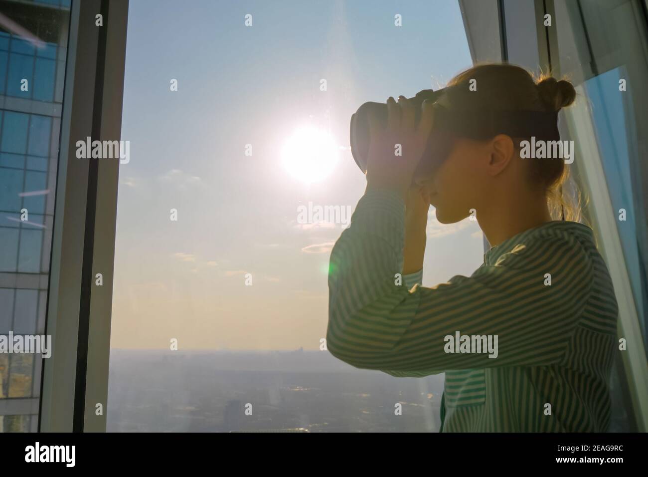 Young woman using virtual reality headset against skyscraper window - VR concept Stock Photo