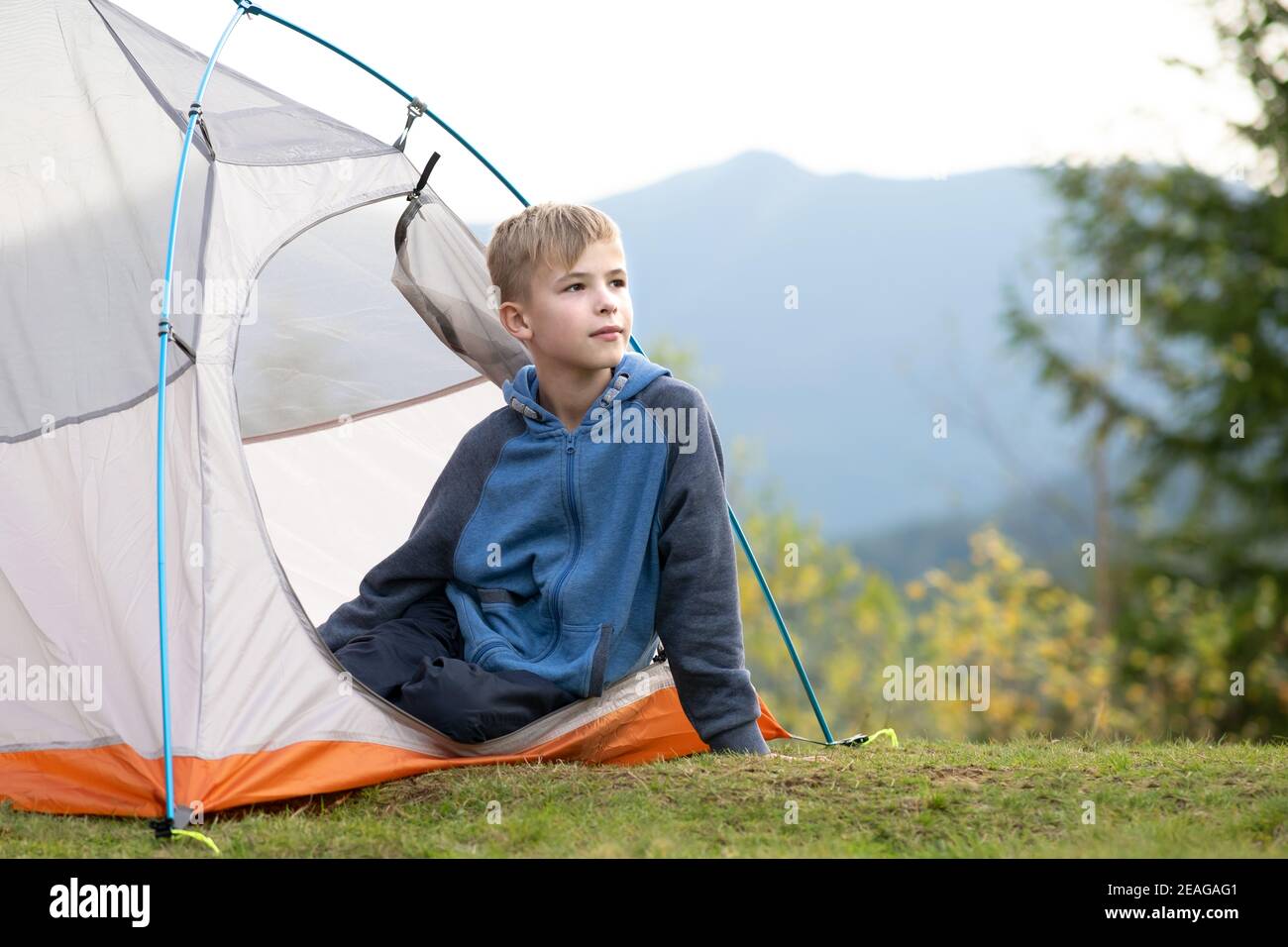 Happy hiker child boy resting in a tourist tent at mountain campsite ...