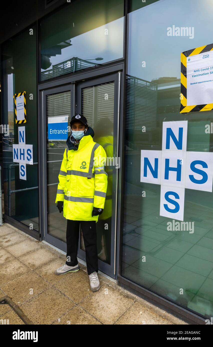 Greeter in a yellow hi-vis jacket outside the entrance to the NHS Covid-19 vaccination site, Victoria Gate, Chobham Road, Woking, Surrey, SE England Stock Photo