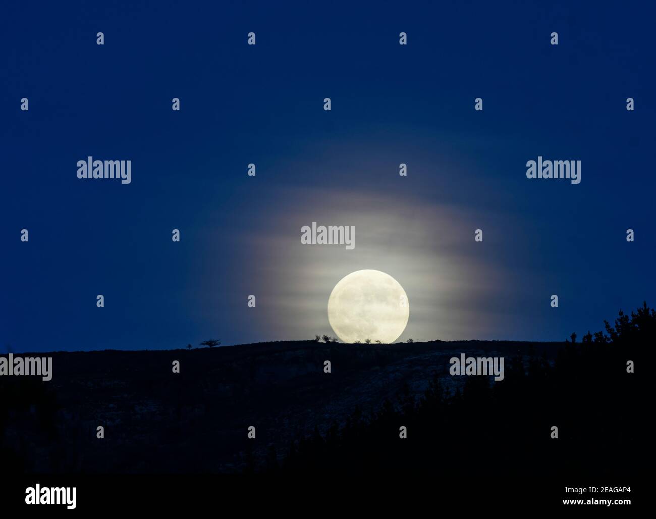 Full moon rising behind the mountain Stock Photo