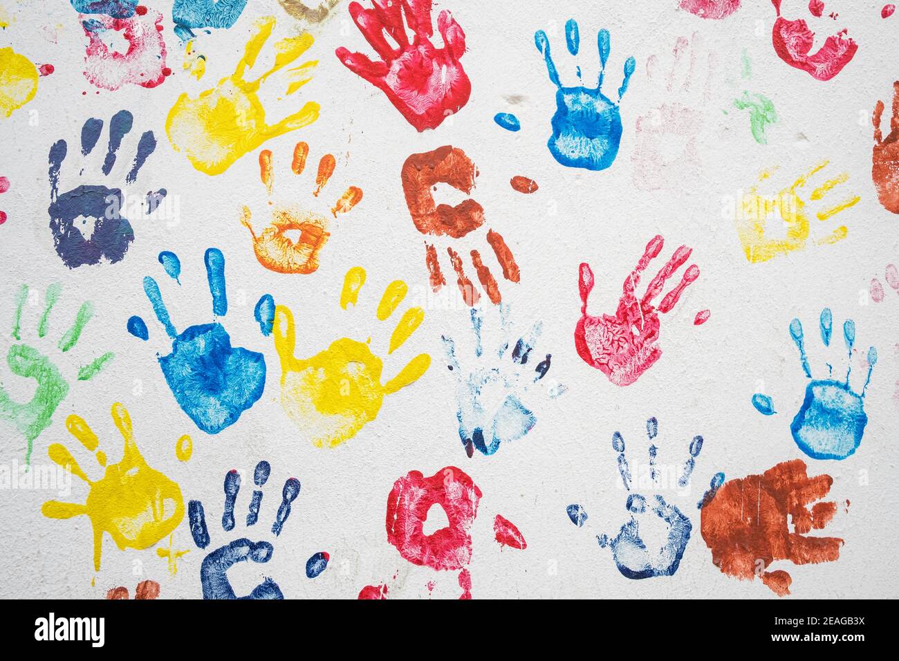 White wall with colorful multicolored hand prints. Stock Photo