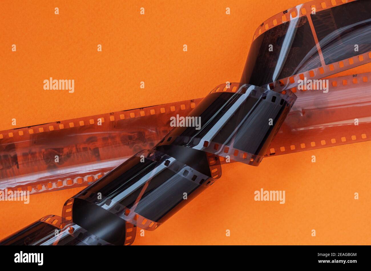 Old 35 mm Photographic film strips, negative on bright orange background, flat lay. Photo, movie cinema concept Stock Photo