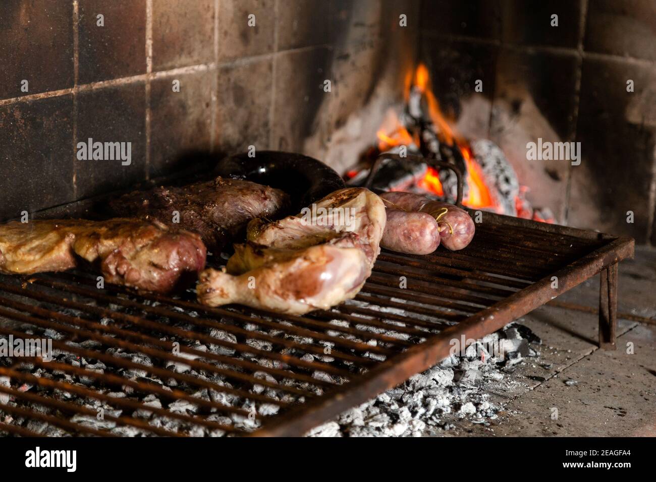 Barbecue. Meat cuts of cow, chicken and pork warming on the embers on an iron grill. Traditional Argentinian bbq. Argentina meal. Stock Photo
