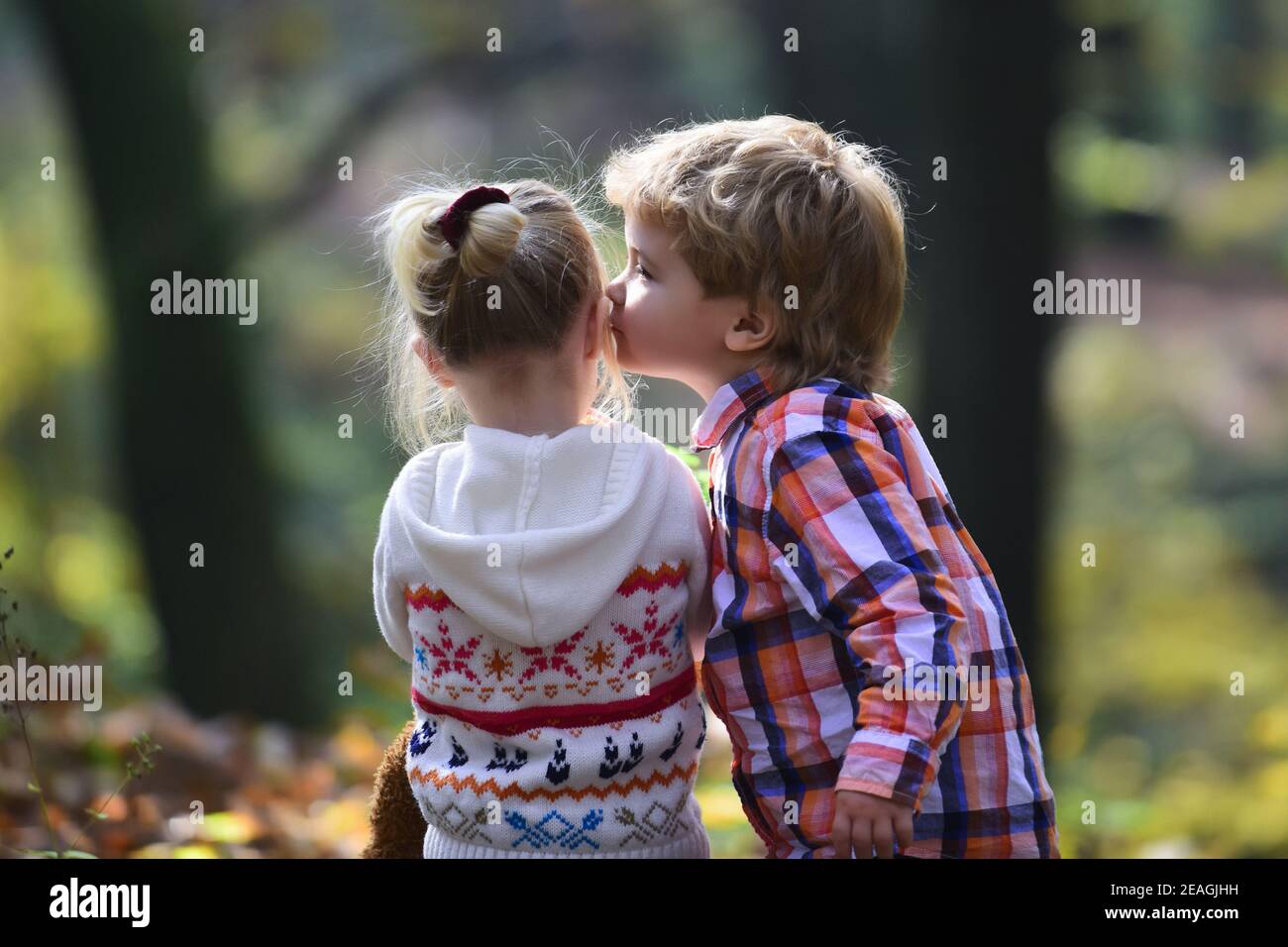 Little boy kiss small girl friend in autumn forest. Brother kiss ...