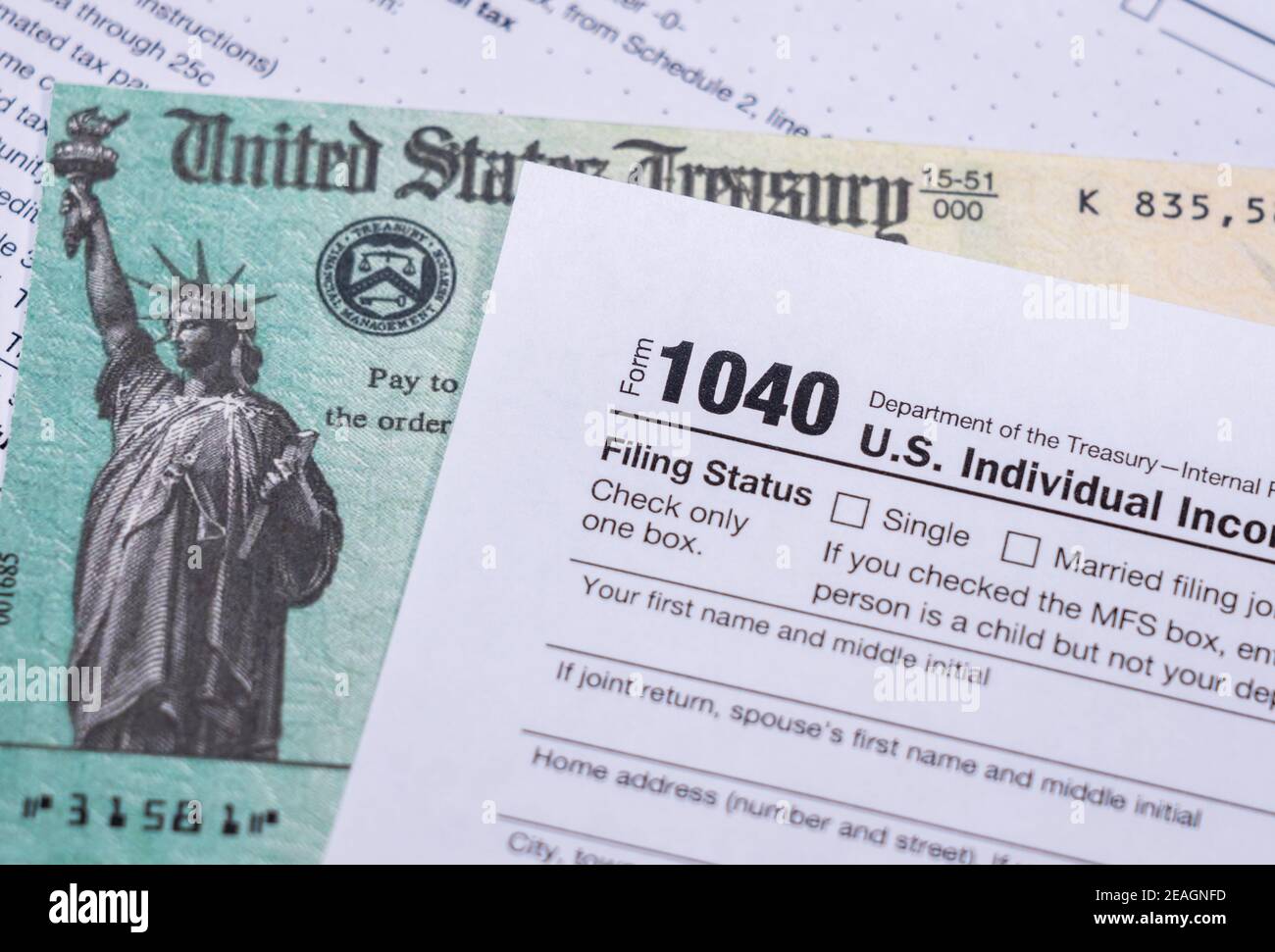 US Treasury stimulus check laying on a form 1040 tax return for 2020 to illustrate questions about qualification for payment Stock Photo