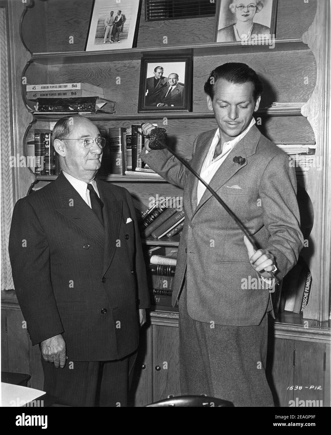 CLARENCE ERICKSEN former Business Manager of Douglas Fairbanks Sr for 25 years now doing same job for DOUGLAS FAIRBANKS Jr presents him with a sword used by his father in The Iron Mask behind the scenes candid during making of THE EXILE 1947 director MAX OPHULS producer Douglas Fairbanks Jr Fairbanks Company / Universal - International Stock Photo