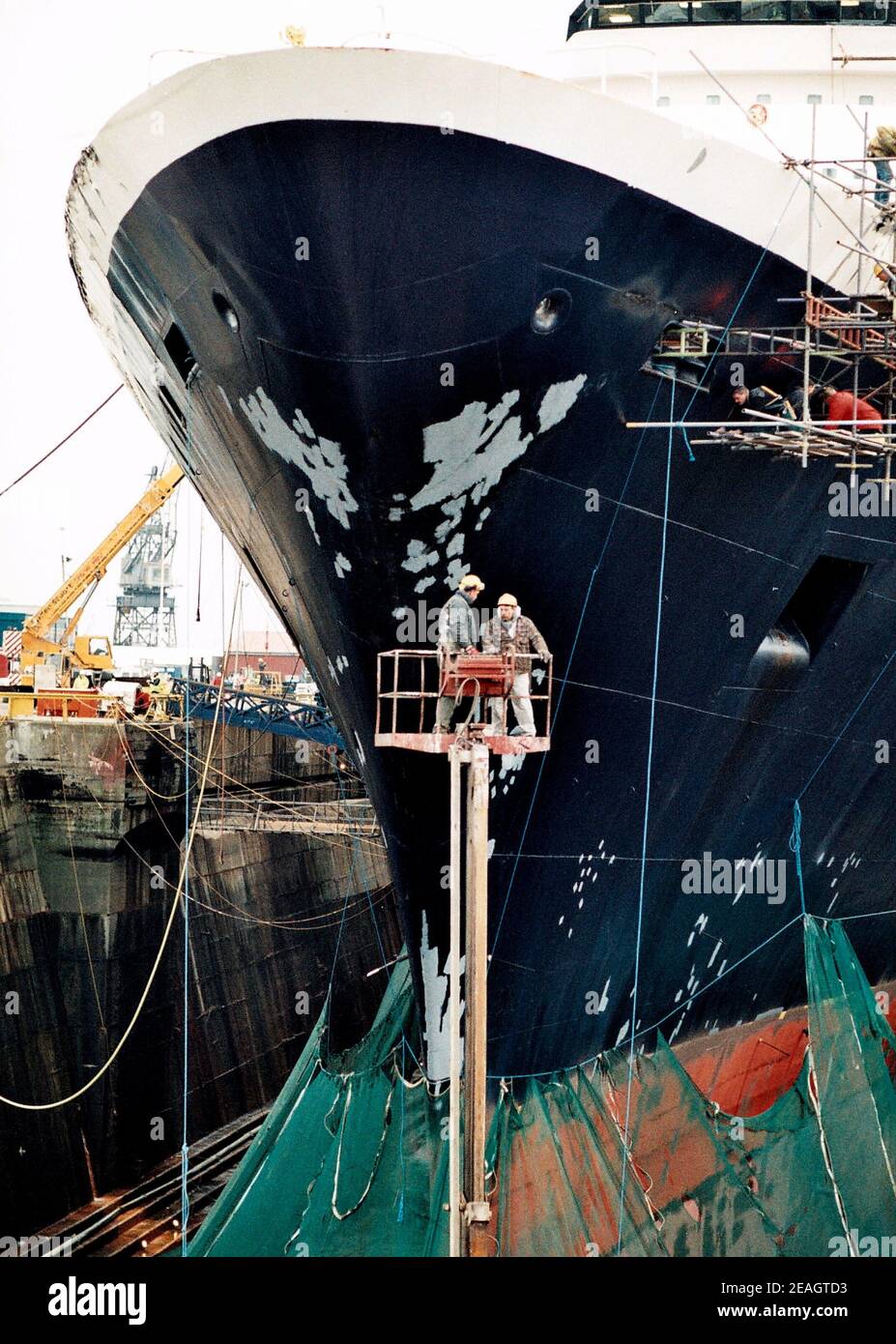 AJAXNETPHOTO. DEC 1996. SOUTHAMPTON, ENGLAND. -  BOW VIEW OF THE CUNARD PASSENGER LINER QUEEN ELIZABETH 2 - QE2 - IN KGV DRY DOCK, HER HULL SHROUDED IN NETTING, UNDERGOES REFIT.  PHOTO:JONATHAN EASTLAND/AJAX.  REF:TC6044 33 13 Stock Photo