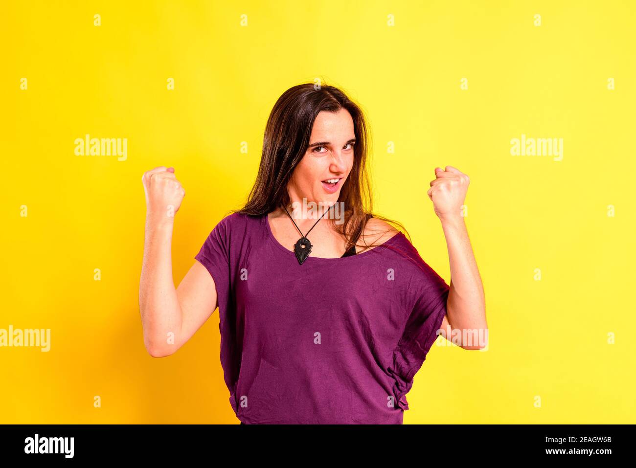 Young woman with proud attitude for a triumph and her achievements made by herself, isolated on yellow background. Stock Photo