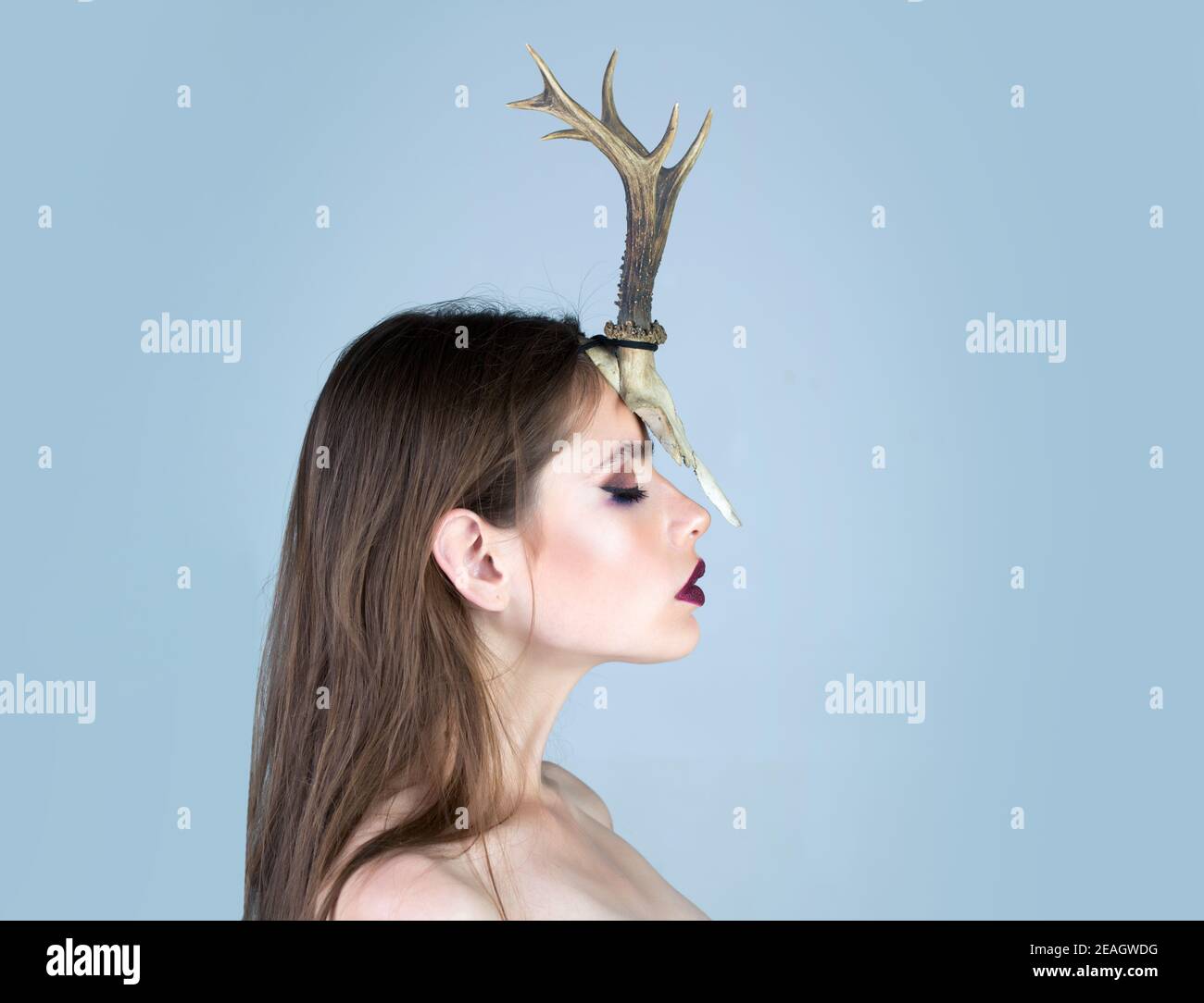 Young woman shaman conjures, she has a horn of an animal on her head. Profile face. Stock Photo