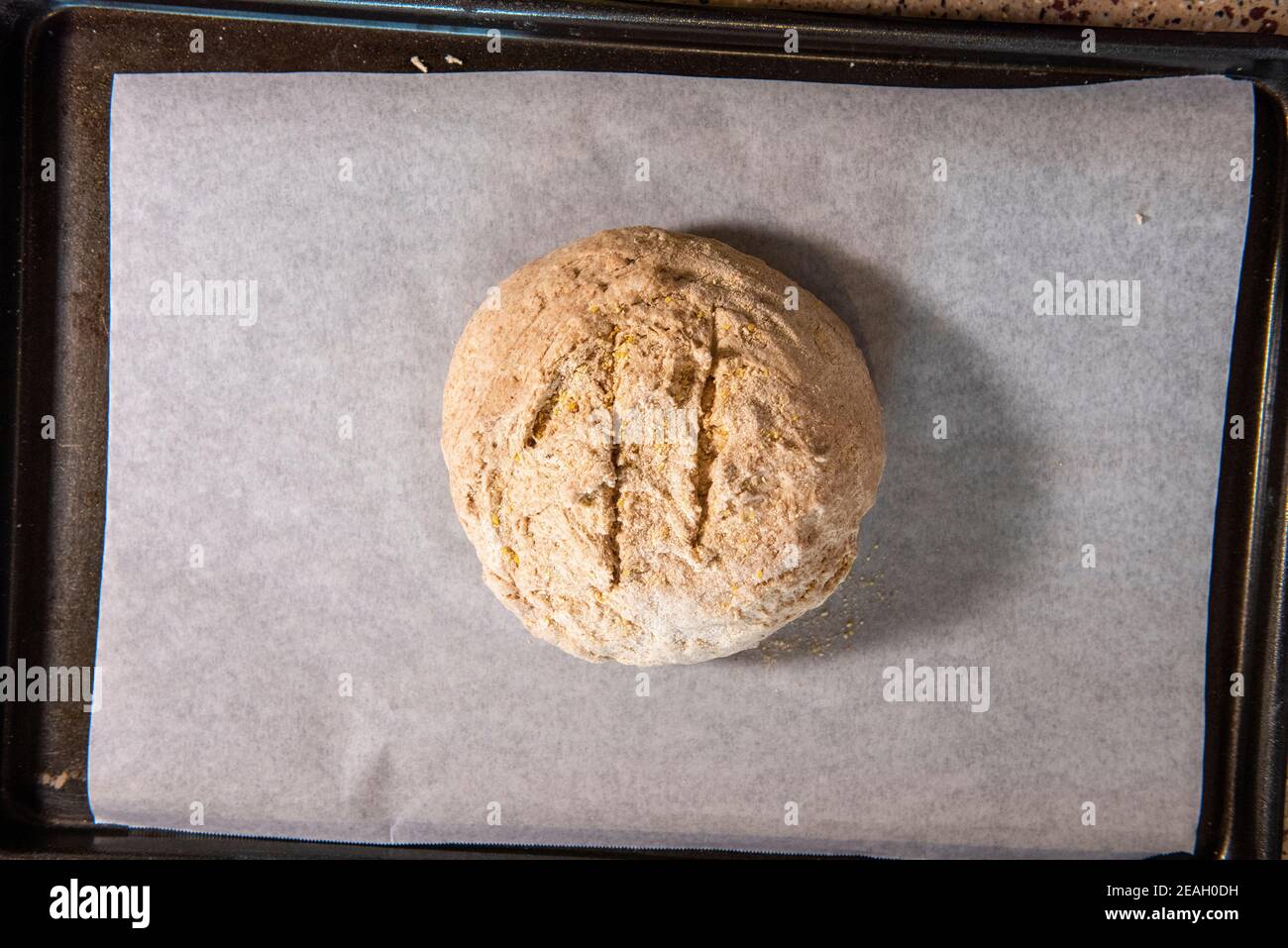 A ball of bread dough is placed on parchment paper and ready to be put into the over to be baked.  Series step-by-step making homemade bread.  Frame 1 Stock Photo