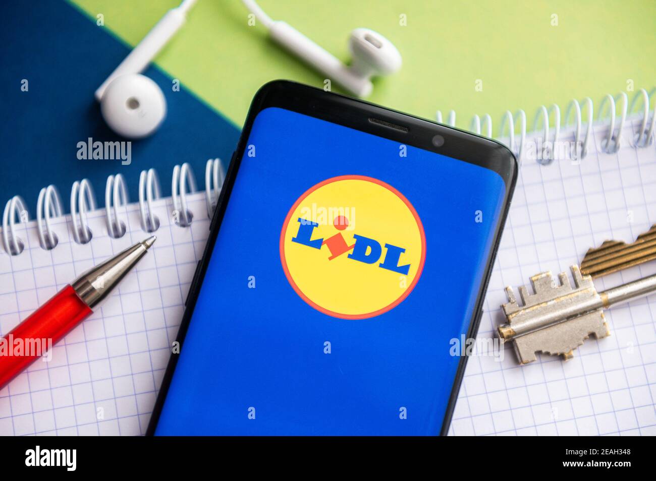 In this photo illustration, a Lidl logo seen displayed on a smartphone with  a pen, key, book and headsets in the background Stock Photo - Alamy