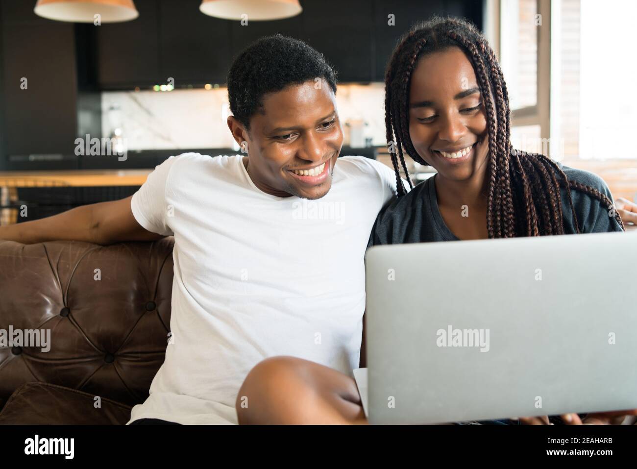 Couple using laptop while sitting on couch at home Stock Photo - Alamy
