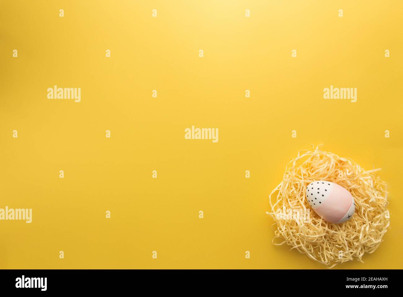 Colored Easter egg in nest on yellow background Stock Photo - Alamy