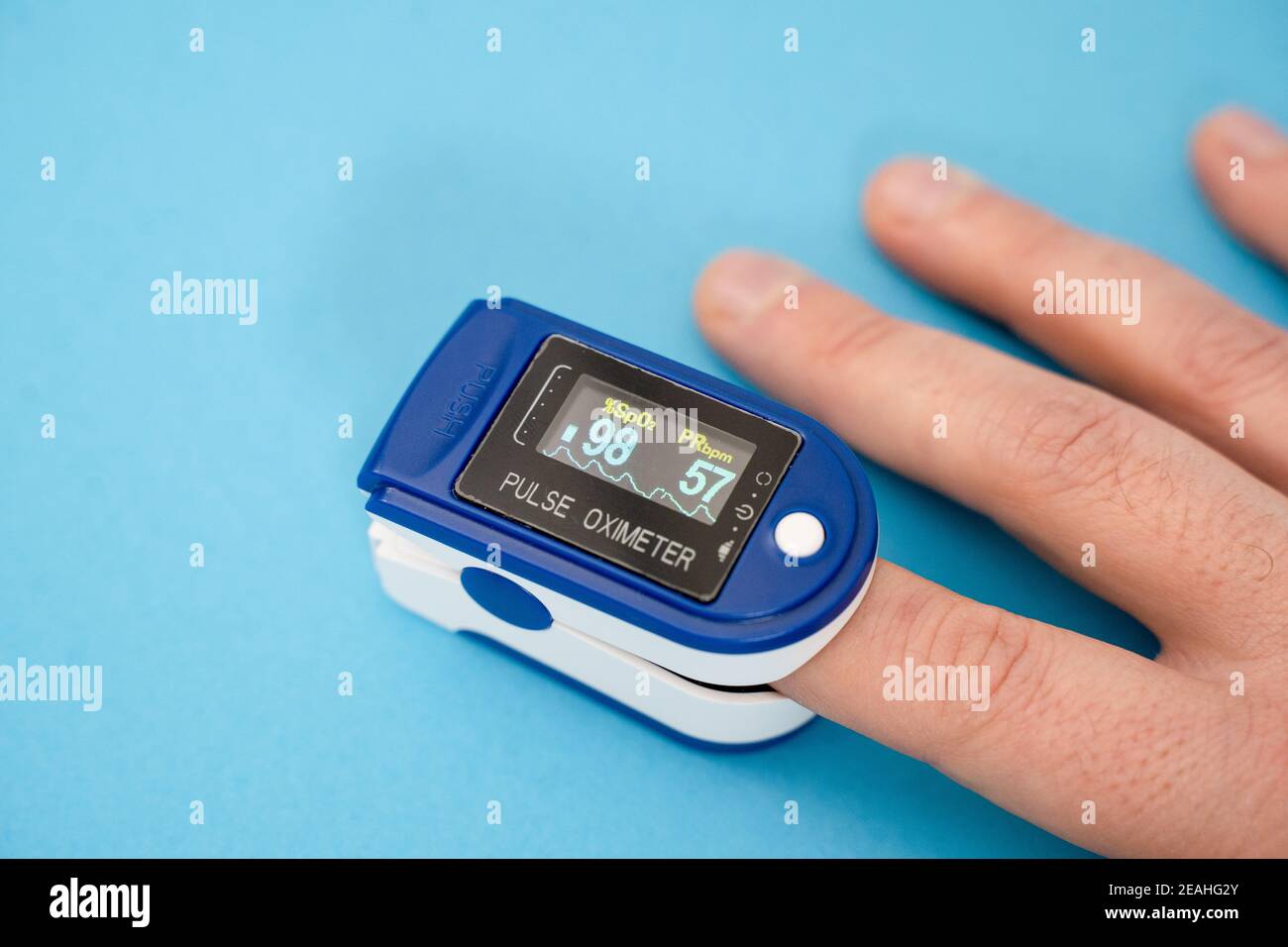 Pulse oximeter, finger digital device to measure oxygen saturation in blood on blue background Stock Photo