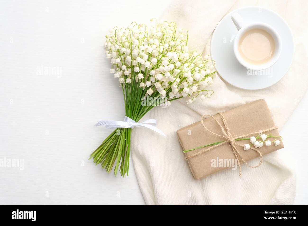 Coffee mug, bouquet of flowers lily of the valley, gift box on white