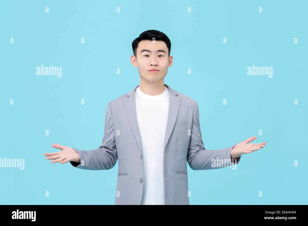 Young Asian man in semi-formal clothes doing open hand gesture isolated on light blue background Stock Photo