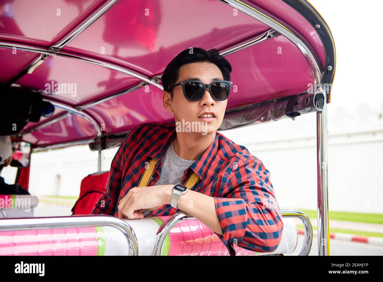 Young Asian tourist man riding on local Tuk Tuk taxi in Bangkok Thailand Stock Photo