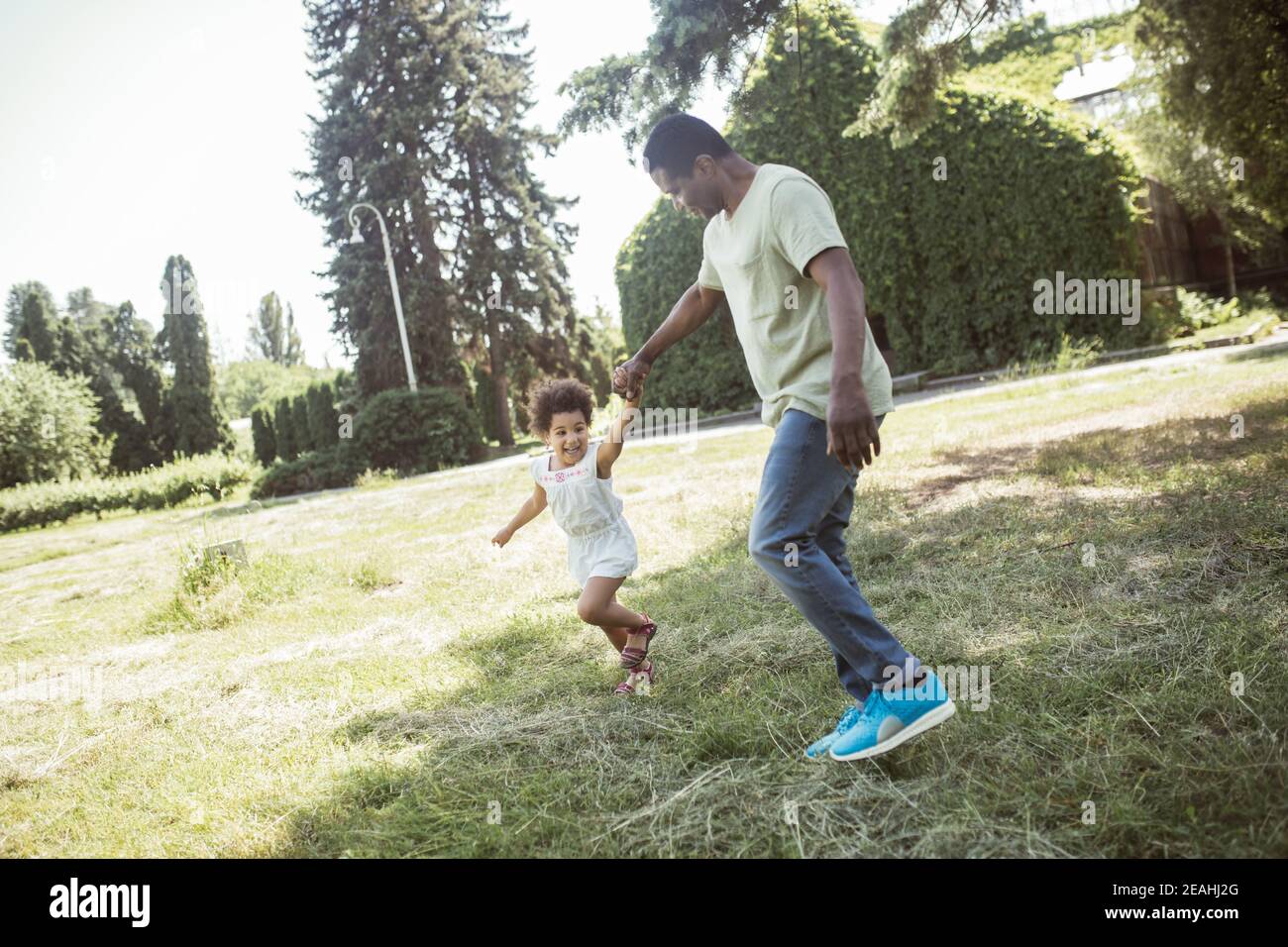 Cute curly kid sitting having great time with her dad Stock Photo