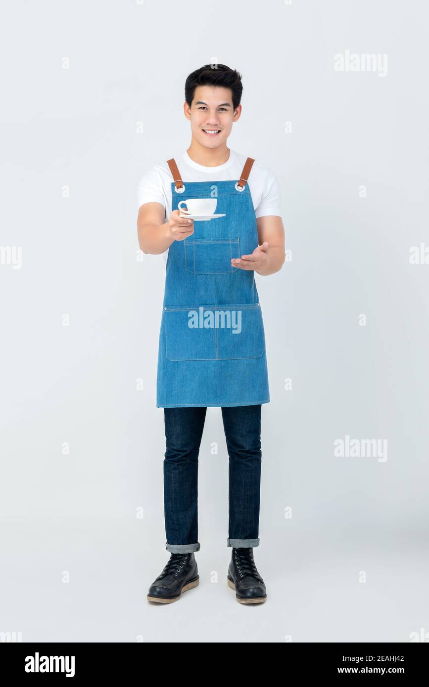 Full lenght of handsome smiling service minded Asian man barista serving a cup of coffee isolated on white background Stock Photo