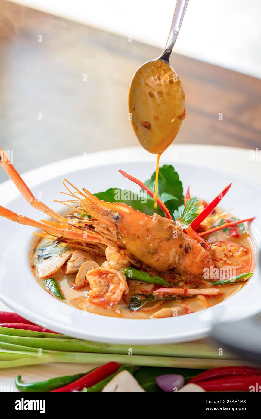 Authentic hot and spicy Tom Yum Kung Thai food with herbs and big prawn in a bowl Stock Photo