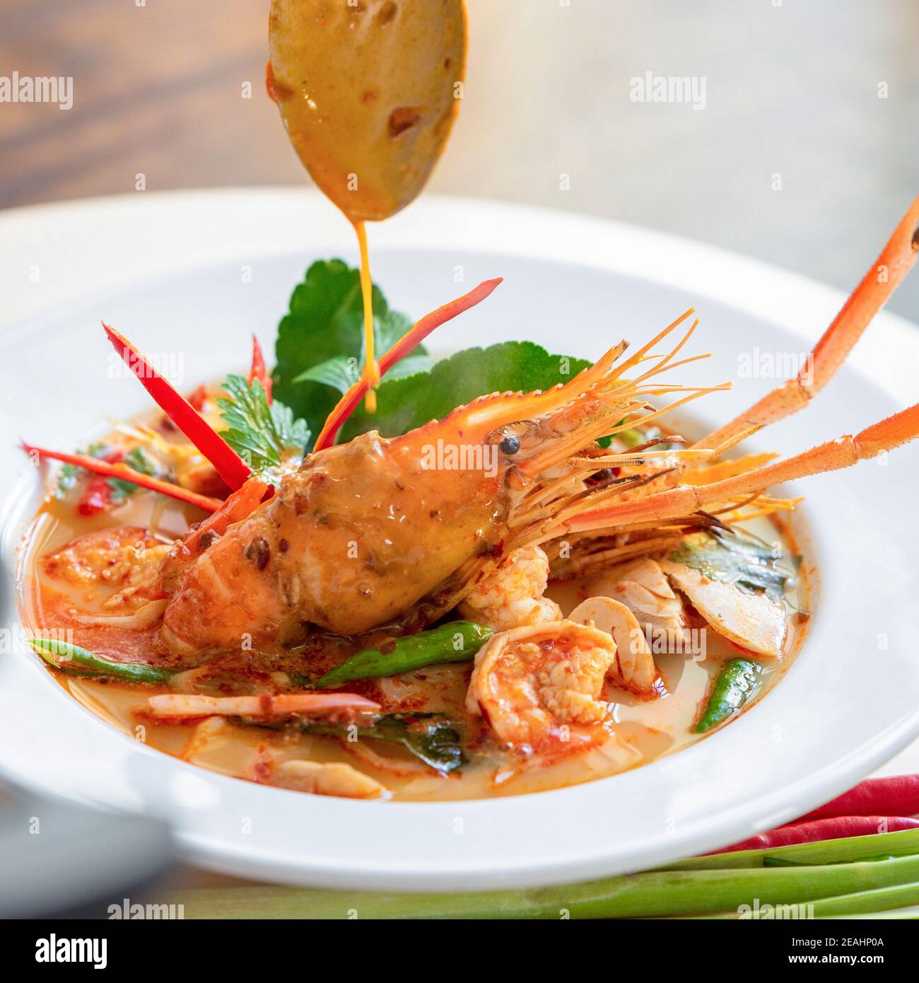 Traditional famous Thai food Tom Yum Kung or hot and spicy prawn soup with mixed herb ingredients in a bowl Stock Photo