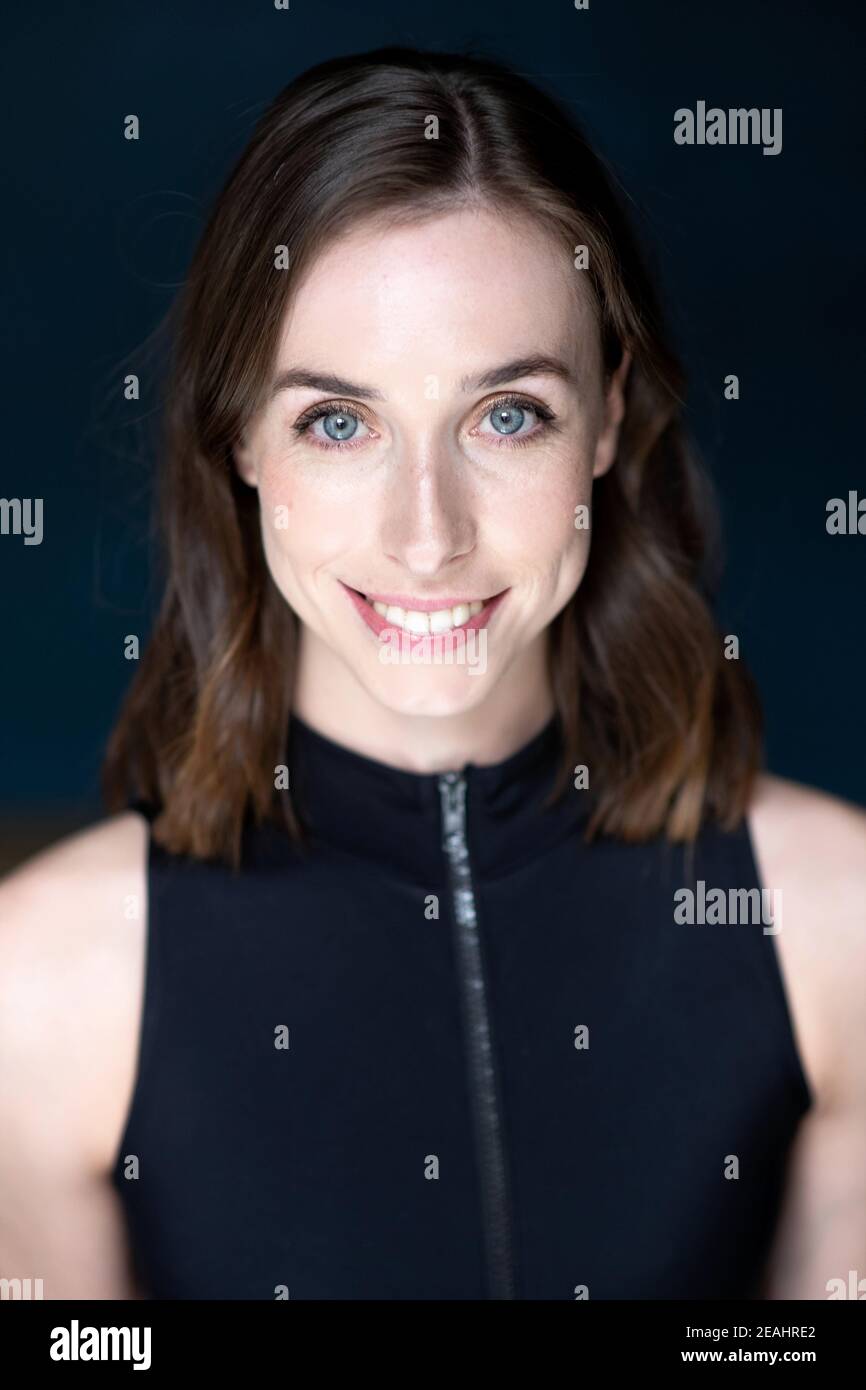 Head and shoulders portrait of young woman with shoulder length brown hair wearing a black top Stock Photo