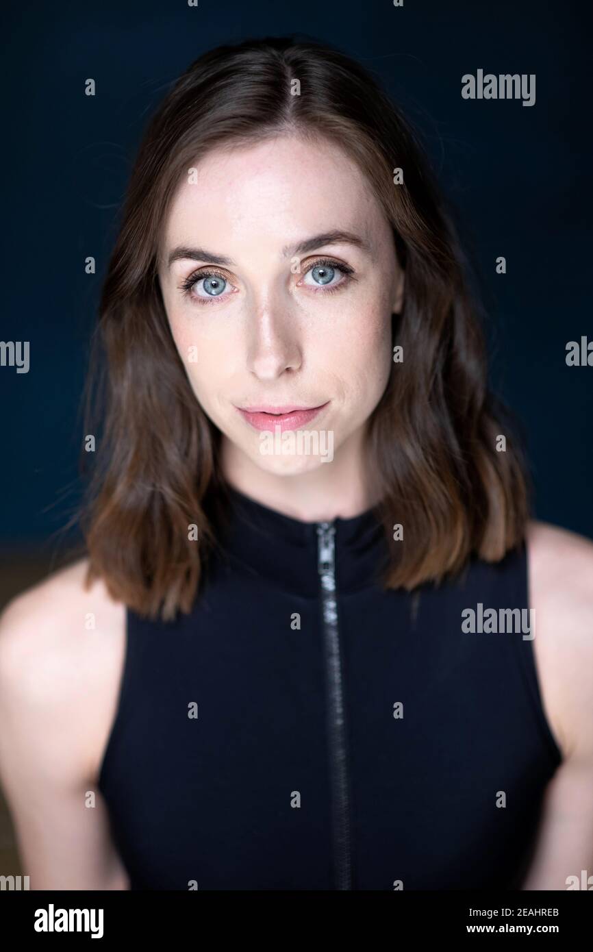 Head and shoulders portrait of young woman with shoulder length brown hair wearing a black top Stock Photo