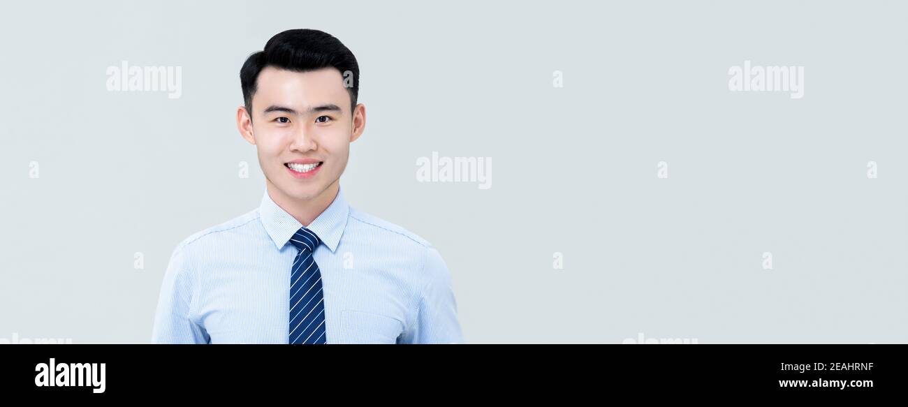 Young handsome Asian professional man in business shirt and tie with fresh clean shaven appearance facing camera and smiling isolated on light gray ba Stock Photo