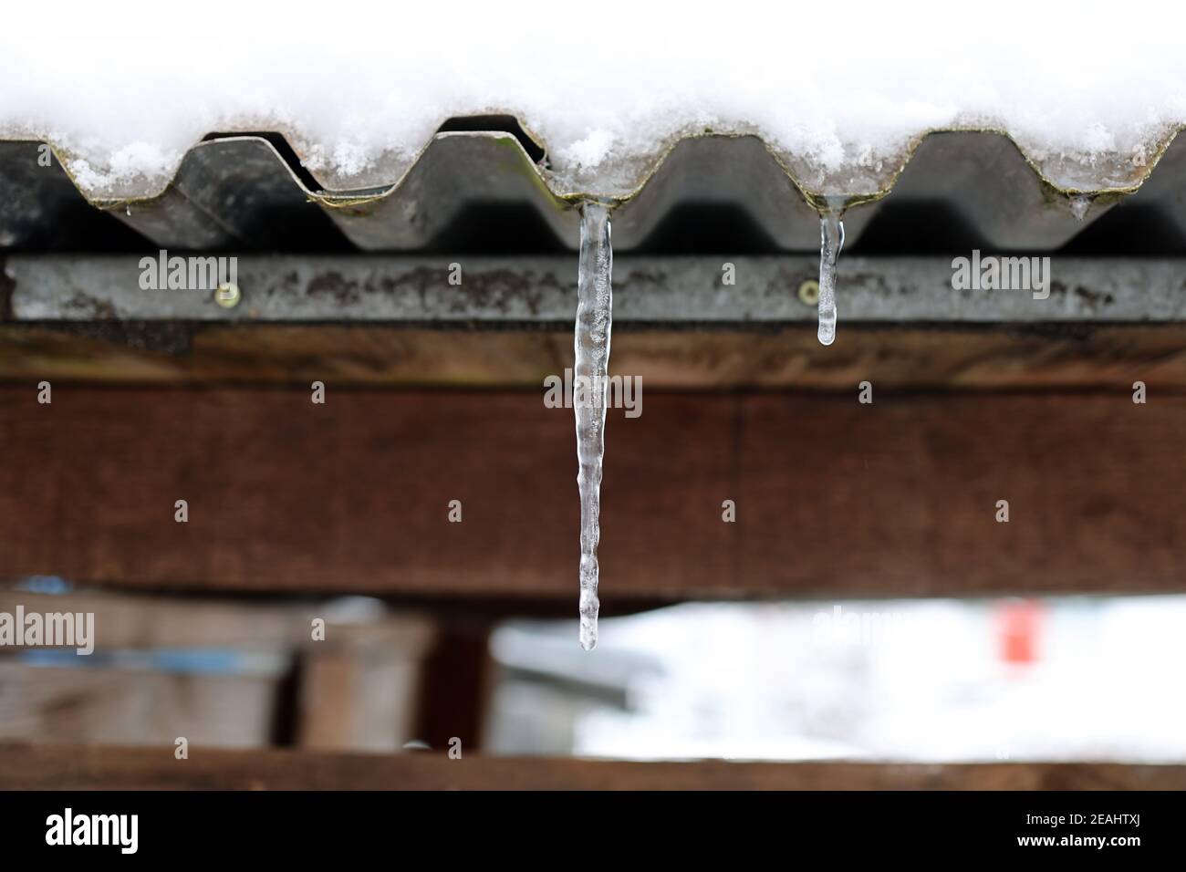 The snow on the roof melts and forms ice icicles Stock Photo