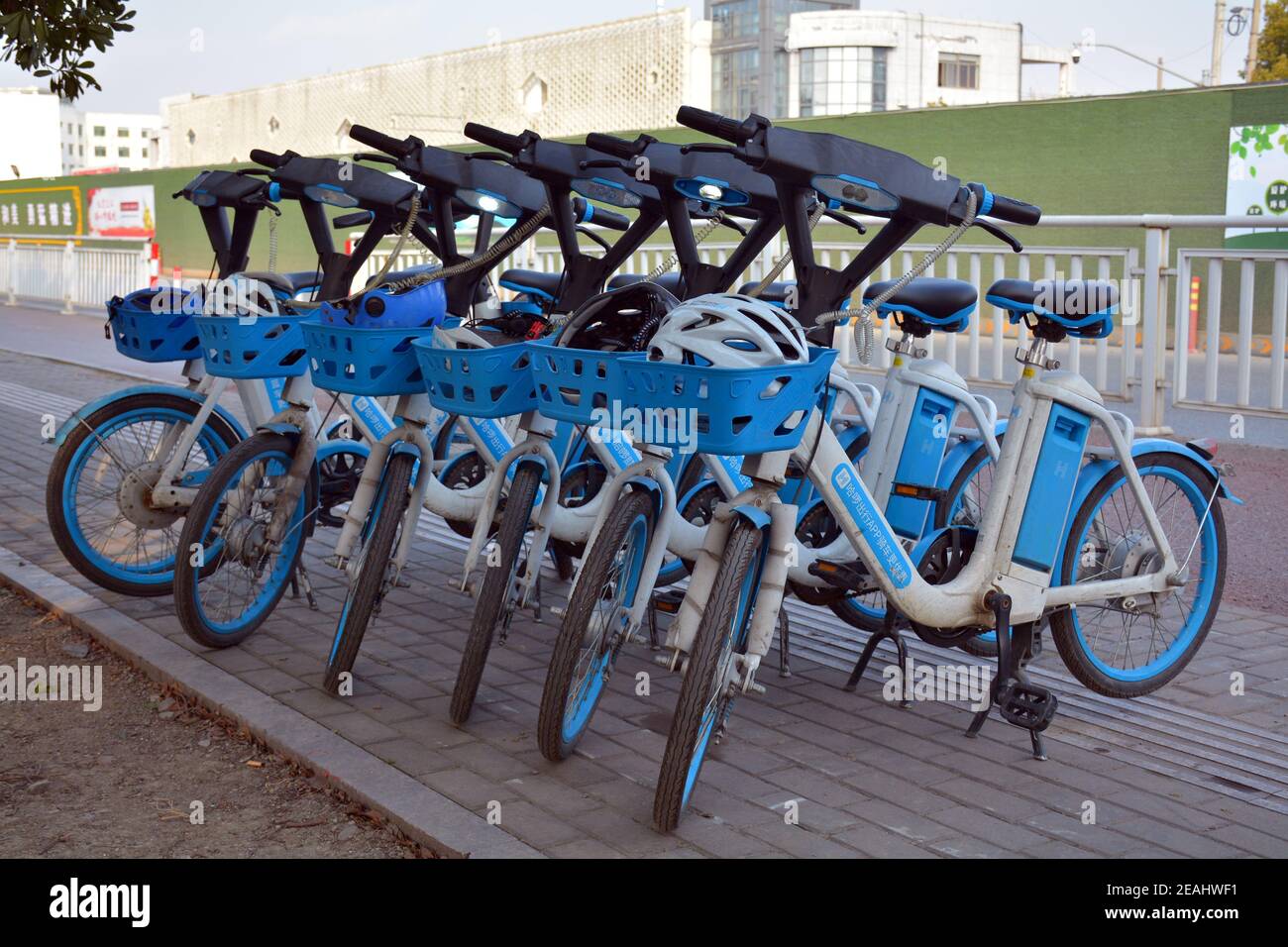 Chinese electric rental bikes on the street in Jiaxing, Zhejiang. Come complete with safety helmet, just scan the barcode to activate and away you go. Stock Photo
