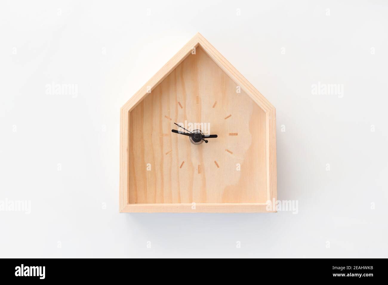 Wooden clock in the shape of house isolated on white background. Minimal concept. Flat lay. Top view. Stock Photo