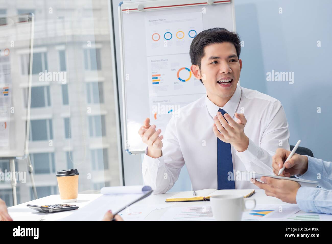 Handsome young Asian businessman talking with colleague at the meeting in office Stock Photo